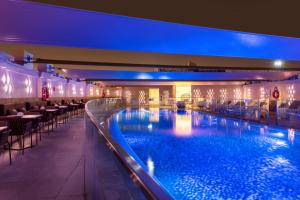 a swimming pool in a hotel with tables and chairs at Crowne Plaza Doha - The Business Park by IHG in Doha