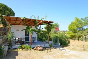 a cottage with a table and chairs under a pergola at Ralaki Cottage in Ralaki