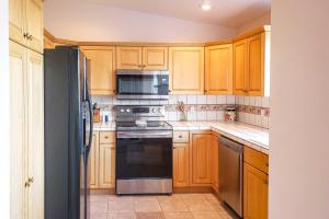 a kitchen with wooden cabinets and a black refrigerator at Condo with Resort Amenities, by Downtown St George! in St. George