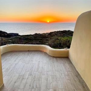 a bench with a view of the ocean at sunset at Villa Antioco in Cala Sapone