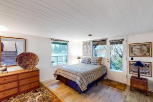 a bedroom with a bed and a dresser and windows at Delake House in Otis
