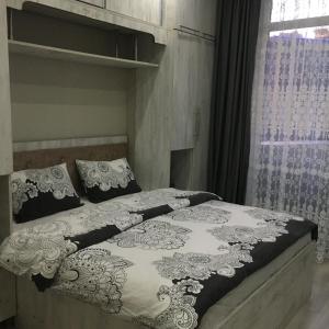 a bed with a black and white blanket and a window at Сдается уютная двухкомнатная квартира с джакузи в Батуми in Batumi