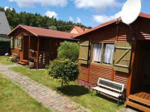 a wooden cabin with a bench in the yard at 2 Bursztyny in Rusinowo +21 photos