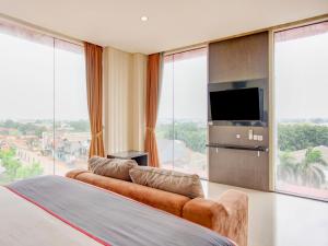a bedroom with a bed and a tv and large windows at SUPER OYO Collection O Hotel Igloo in Bekasi
