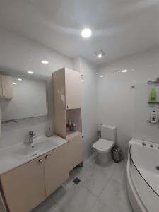 a white bathroom with a toilet and a sink at Сдается уютная двухкомнатная квартира с джакузи в Батуми in Batumi
