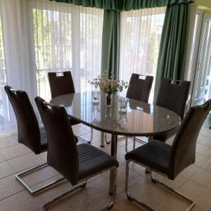 a dining room with a glass table and chairs at Bokréta Üdülő in Mezőkövesd +19 photos