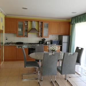 a kitchen with wooden cabinets and a table and chairs at Bokreta Udulohaz in Mezőkövesd