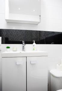 a white bathroom with a sink and a toilet at Luxus Apartament Alex in Gdynia
