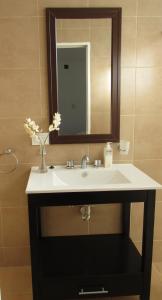 ein Waschbecken mit einem Spiegel und einer Vase aus Blumen in der Unterkunft Médanos Patagonia in Las Grutas