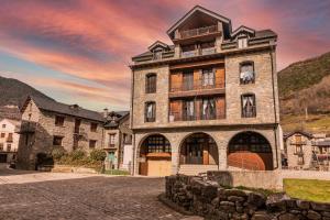 a large stone building with a sunset in the background at Santa Cruz in Broto