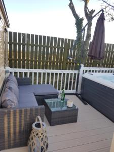a patio with a couch and a table and a hot tub at Hillingworth's Hot Tub Retreat - St Cyrus in Garvock