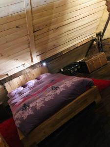 a bed in a room with a wooden wall at Mante et Nana in Durbuy