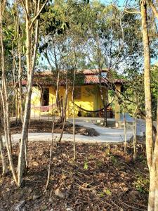 a yellow building in the middle of a forest of trees at Espaço Terra Dourada, Ibicoara, Chap Diamantina in Ibicoara