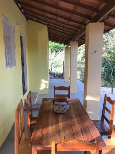 Espaço Terra Dourada, Ibicoara, Chap Diamantina في إيبوكوارا: طاولة خشبية مع كراسي و مزهرية على الشرفة