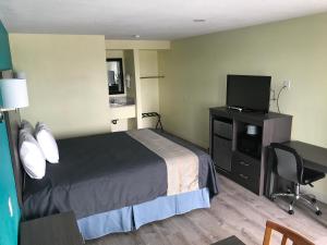 ein Hotelzimmer mit einem Bett und einem Schreibtisch mit einem TV in der Unterkunft Gila Bend Lodge in Gila Bend