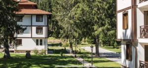 a building with a yard with trees and a street at Апартамент в комплекс Смолянски езера in Smolyan