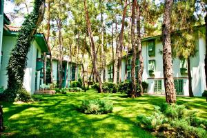 un patio verde con árboles y un edificio en Ulusoy Kemer Holiday Club - Kids Concept, en Kemer