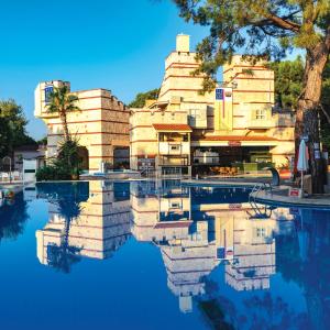 uma piscina de água com um edifício ao fundo em Ulusoy Kemer Holiday Club - Kids Concept em Kemer