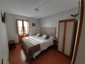 1 dormitorio con cama blanca y ventana en La Casona del Jou en Ortiguero