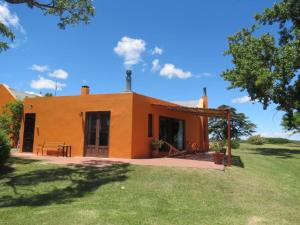 una pequeña casa naranja con césped delante en Estancia San Pedro, en Colonia del Sacramento