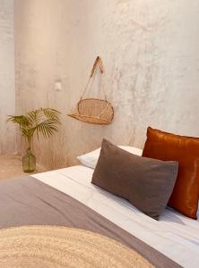 1 dormitorio con 1 cama con una cesta en la pared en Apartments & Suites MADRE Holbox Self-Check IN, en Isla Holbox