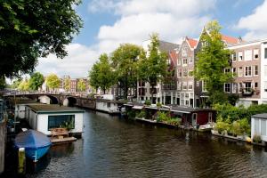 um rio com casas e uma ponte e um barco em Old City Centre apartments - Nieuwmarkt area em Amsterdã