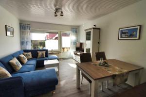 ein Wohnzimmer mit einem blauen Sofa und einem Tisch in der Unterkunft Ferienkate Norddeich in Norddeich