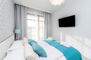 ein Bett mit blauen und weißen Kissen und einem Fenster in der Unterkunft Bright - Neptun Park by OneApartments in Danzig