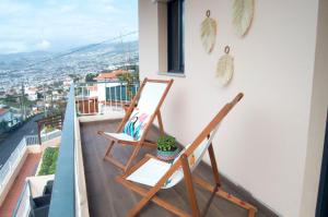 Duas cadeiras numa varanda com vista para a cidade em Villa Reis Sao Goncalo no Funchal