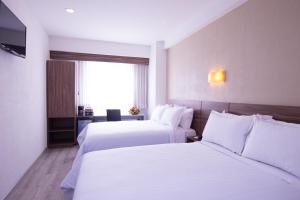 a hotel room with two beds and a window at Crown Victoria Hotel in Querétaro