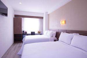 een hotelkamer met 2 bedden en een raam bij Crown Victoria Hotel in Querétaro