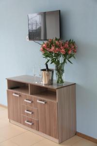 a wooden cabinet with a vase with flowers on it at Apartamenty in Veseloe in Adler