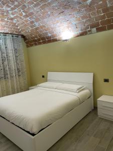 uma cama branca num quarto com uma parede de tijolos em Residenza Nikol em Casale Monferrato