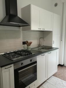 a kitchen with white cabinets and a stove top oven at la casa di Camilla in Sori