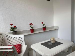 a white table and a white chair with flowers on a shelf at Apartman Travnik in Travnik