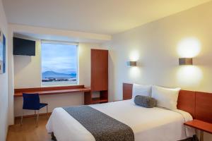 a hotel room with a bed and a window at One Puebla FINSA in Puebla