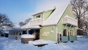 una casa verde con nieve encima en Aare kodumajutus Sandri tuba, en Tammiku