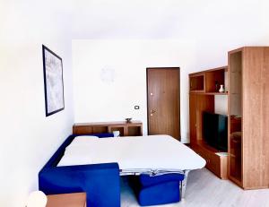 Oliveto LarioにあるVictoria Apartmentのテーブル、青い椅子、テレビが備わる客室です。