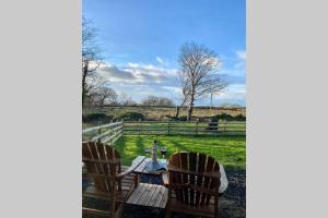 einen Tisch und Stühle auf einem Feld mit einem Zaun in der Unterkunft Lle Mary - Beautiful views, Hot tub, Secluded, Dog Welcome, Barmouth in Llanddwywe