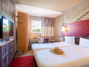 Cette chambre d'hôtel comprend 2 lits avec un chapeau. dans l'établissement ibis Manosque Cadarache, à Manosque