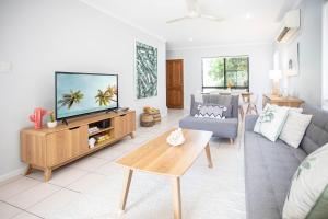 uma sala de estar com um sofá e uma televisão em Paradise Palms CLOSE TO BEACH, WIFI, 2 BEDROOMS em Airlie Beach