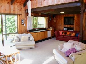 a living room with two couches and a kitchen at Lakeside Villa - Lake Rotoiti Holiday Home in Okere Falls