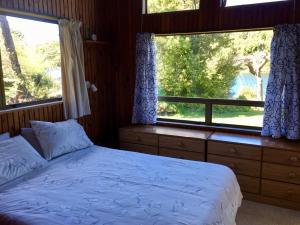 Okere Falls的住宿－Lakeside Villa - Lake Rotoiti Holiday Home，一间卧室设有一张床和两个窗户。