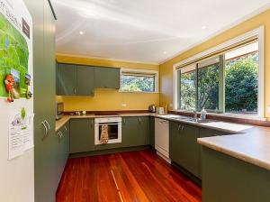 a large kitchen with green cabinets and wood floors at Sawmillers Retreat - Arrowtown Holiday Home in Arrowtown