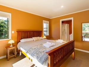 a bedroom with a large bed and two windows at Sawmillers Retreat - Arrowtown Holiday Home in Arrowtown