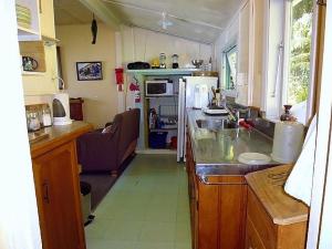 een kleine keuken met een wastafel en een fornuis bij Cottage on The Beach - Moetapu Bay Bach in Whatanihi
