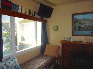 un soggiorno con finestra, divano e TV di Cottage on The Beach - Moetapu Bay Bach a Whatanihi
