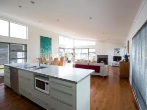 an open kitchen and living room with a couch at Waikanae Retreat - Waikanae Beach Holiday Home in Waikanae