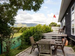 un patio avec une table, des chaises et un drapeau dans l'établissement Waikanae Retreat - Waikanae Beach Holiday Home, à Waikanae