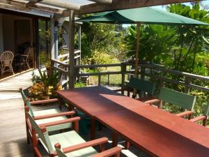 een houten tafel en stoelen met een parasol op een terras bij Bush Beach Delight - Onetangi Holiday Home in Onetangi